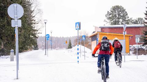 Kaksi pyöräilijää pyörätiellä talvikelillä Muotialassa.