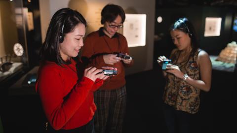 Three young people listening to audio guides in Moomin Museum.