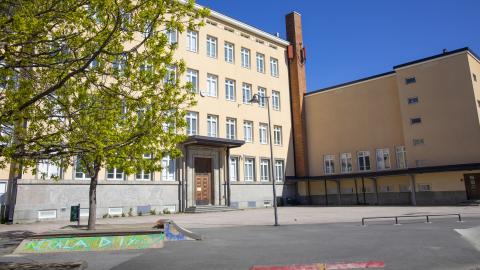 Nekalan koulu on kellertävä nelikerroksinen entinen koulurakennus, jonka pihamaalla on lehtipuita.