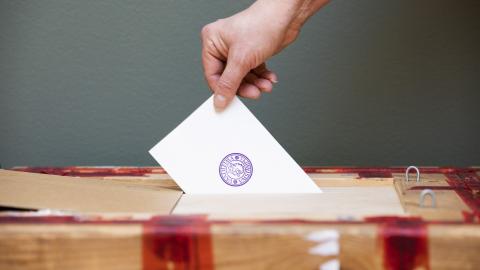 A hand putting an election ticket in to a ballot box.