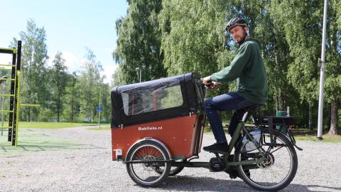 A person riding a cargo bike in a park.