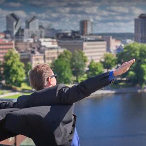 A person spreads their arms like the wings of an aeroplane. Tampere cityscape in the background. 