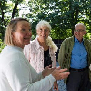 Neljä senioria keskustelee vilkkaasti ulkona Koskipuistossa.