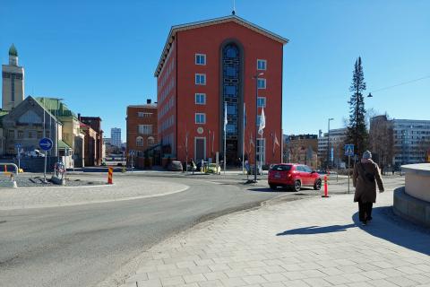 Auto ja kävelijä Lapintien kiertoliittymässä, hotelli Tammer ja paloasema taustalla.