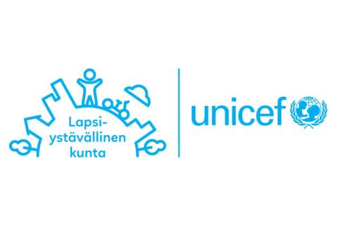 Unicefin Lapsiystävällinen kunta -tunnuksessa on piirretty kaari, jossa erottuu lapsen hahmo kaupungin keskellä. Sen alapuolella on teksti Lapsiystävällinen kunta. Kuvan vieressä on Unicefin nimi ja logo.