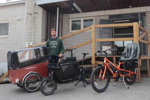 Three different cargo bikes on display with a person standing behind them.